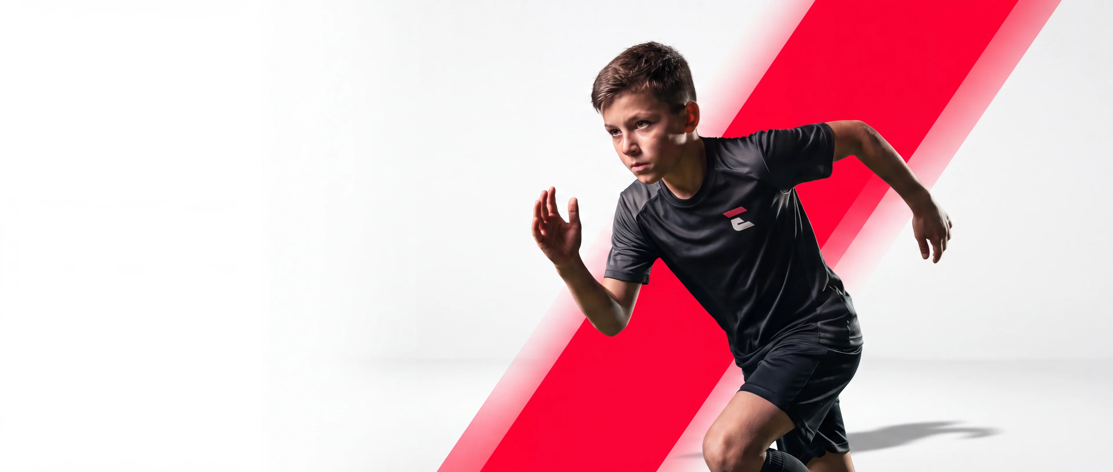 A young Ecole Sports athlete sprinting past a bold red slash