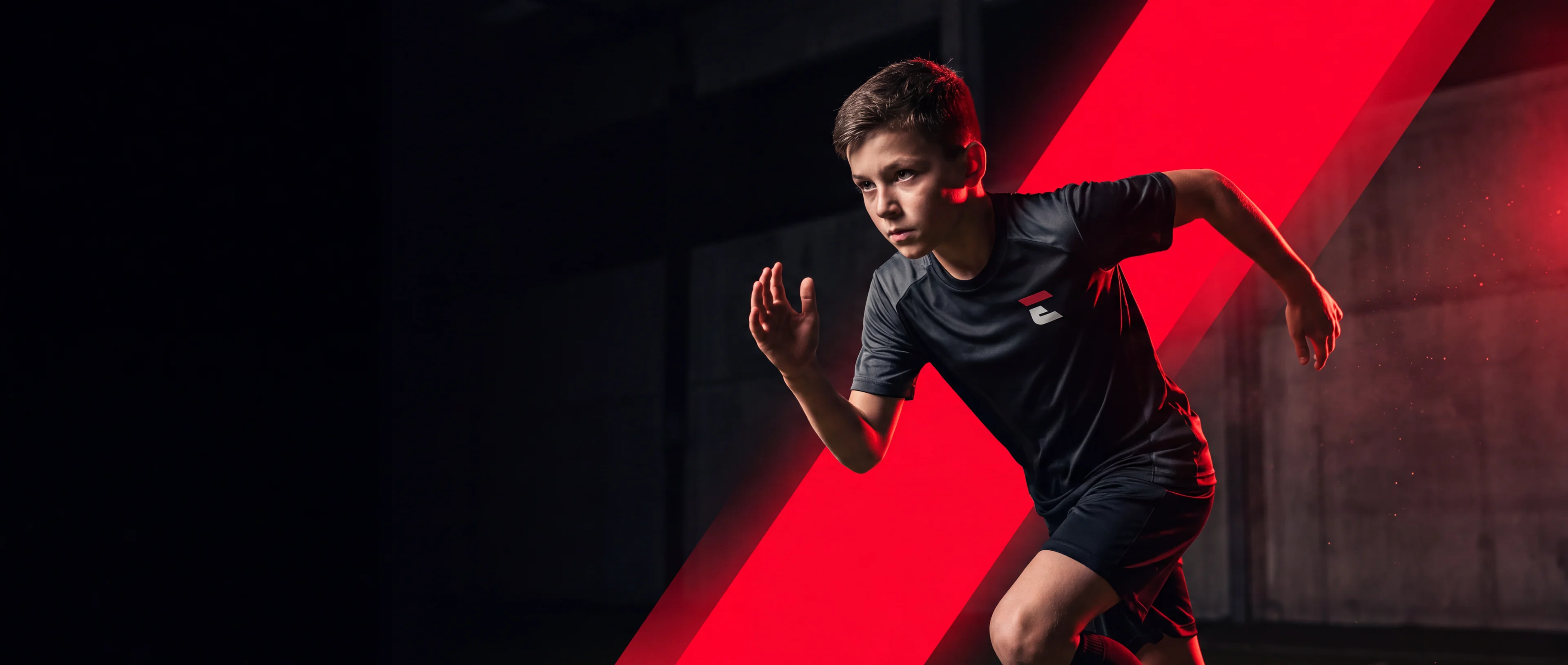 A young Ecole Sports athlete sprinting past a bold red slash